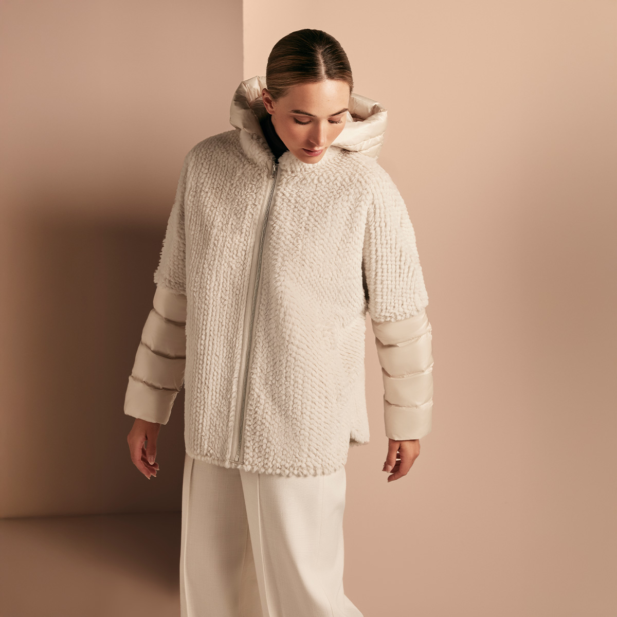 Dame trägt eine cremefarbene Kunstfelljacke mit gesteppten Ärmeln