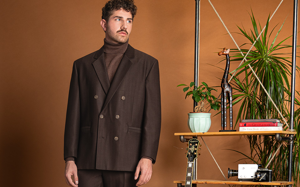 Brauner Doppelreiher-Anzug mit Rollkragenpullover, elegant im Innenraum präsentiert