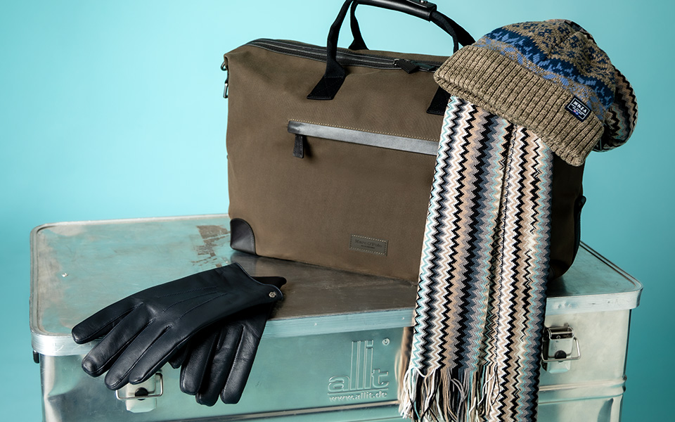 Olivgrüne Umhängetasche aus Nylon mit schwarzen Lederhandschuhen und gemustertem Wollschal