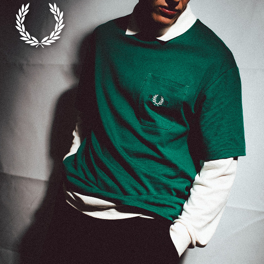 Mann in grünem T-Shirt mit Brusttasche über weißem Longsleeve