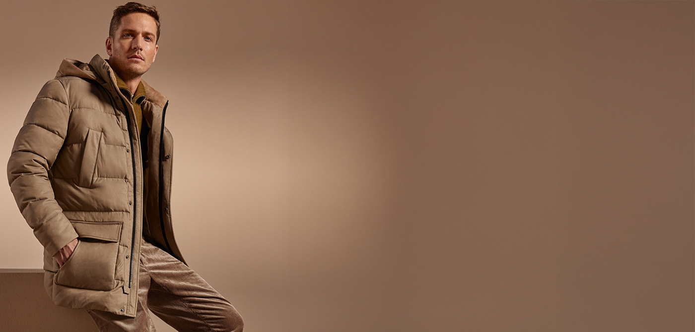 Mann in beiger Daunenjacke mit Kapuze, lässig kombiniert mit Cordhose