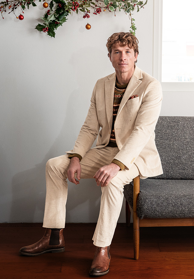 Hellbeiger Cordanzug mit gemustertem Pullover und braunen Chelsea-Boots, sitzend präsentiert