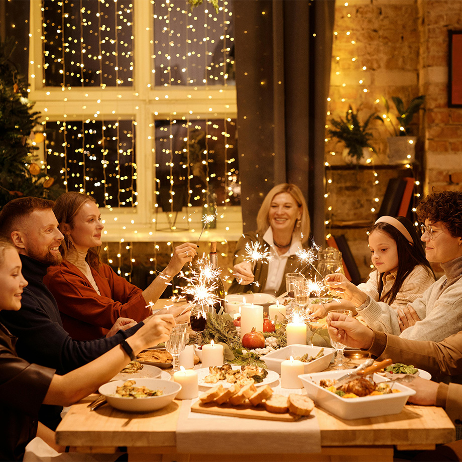 Familie beim Abendessen mit Wunderkerzen, festlich dekorierter Tisch, Lichterketten im Hintergrund