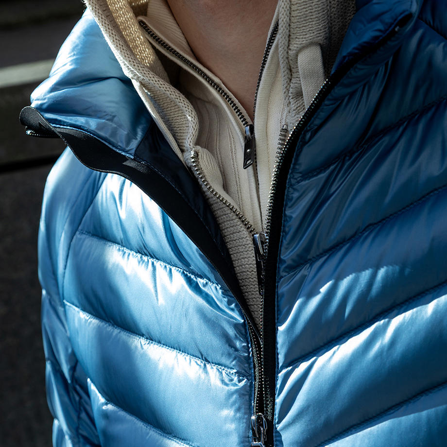 Eine Nahaufnahme des Layeringlooks aus Stricktroyer, Strickjacke mit Kapuze und Steppjacke