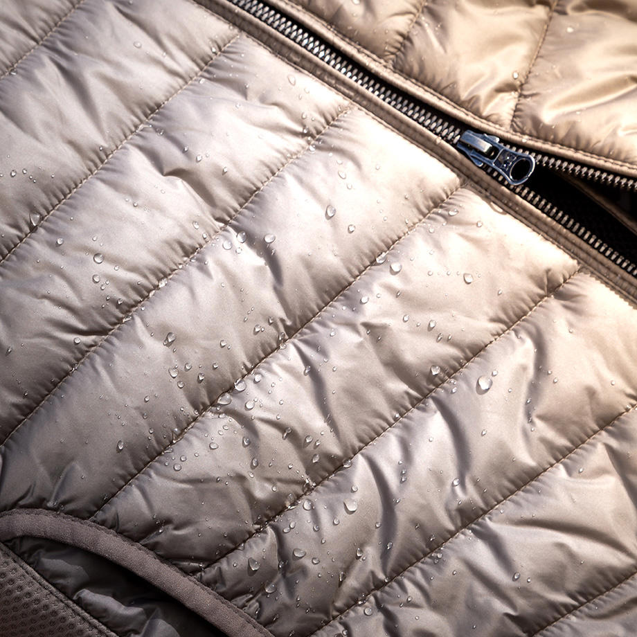 Eine Nahaufnahme einer Steppjacke. Regentropfen glitzern auf ihrer Oberfläche.