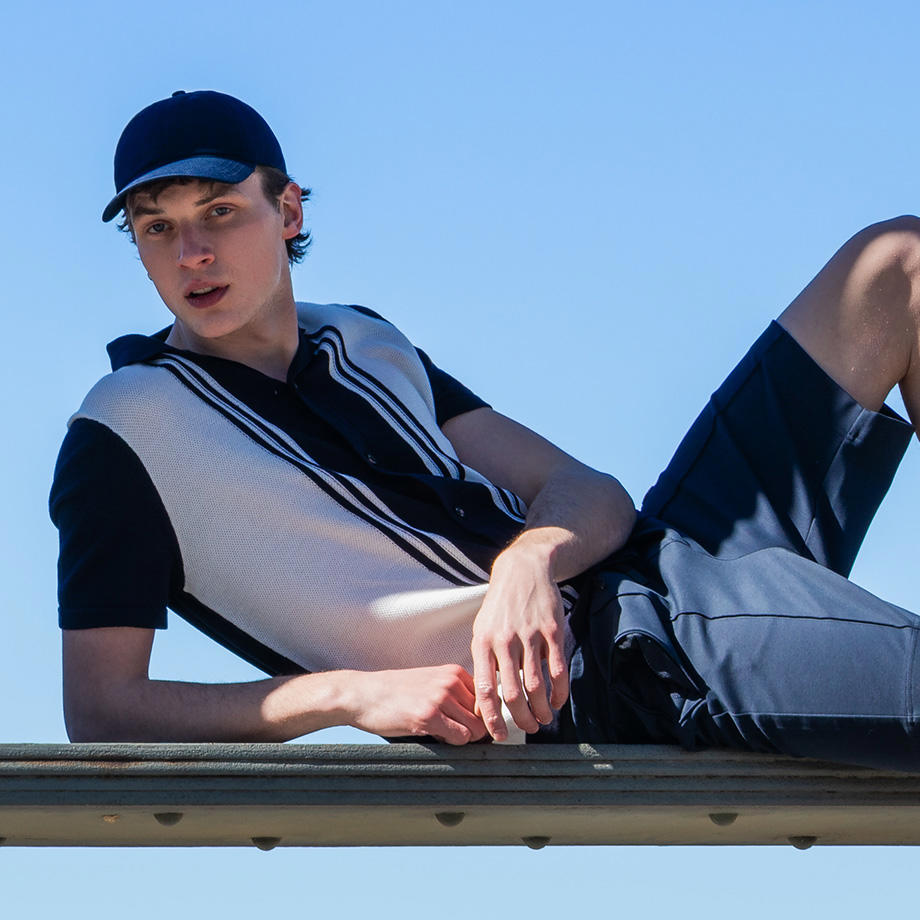 Ein Mann in einem blau-weißen Outfit posiert liegend auf einer Brücke