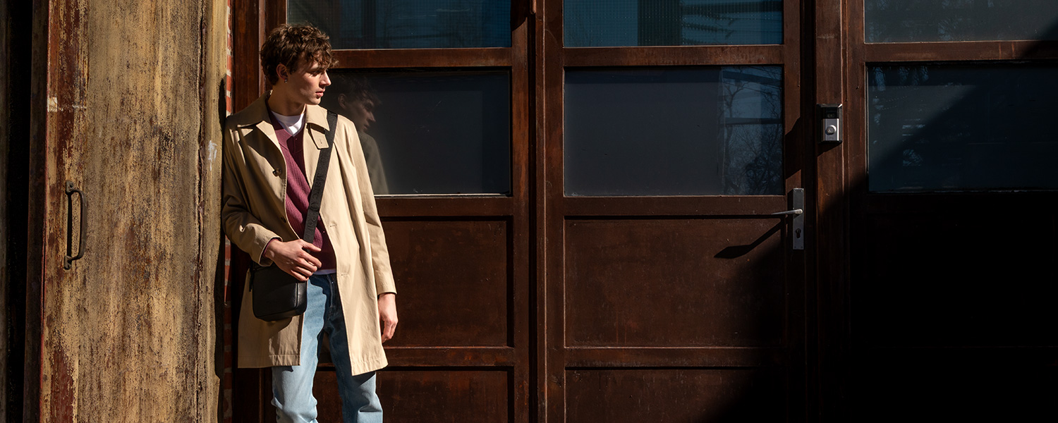 beiger Trenchcoat, gestylt mit V-Neck-Pullover und Jeans