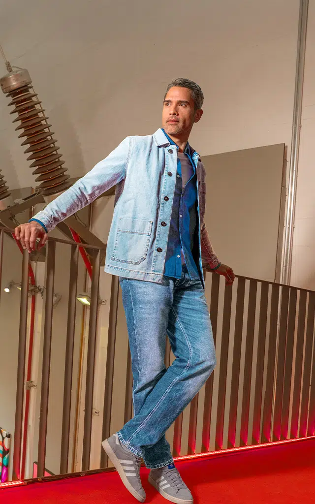 Ein Mann lehnt an einem Geländer. Er trägt einen Full-Denim-Look.