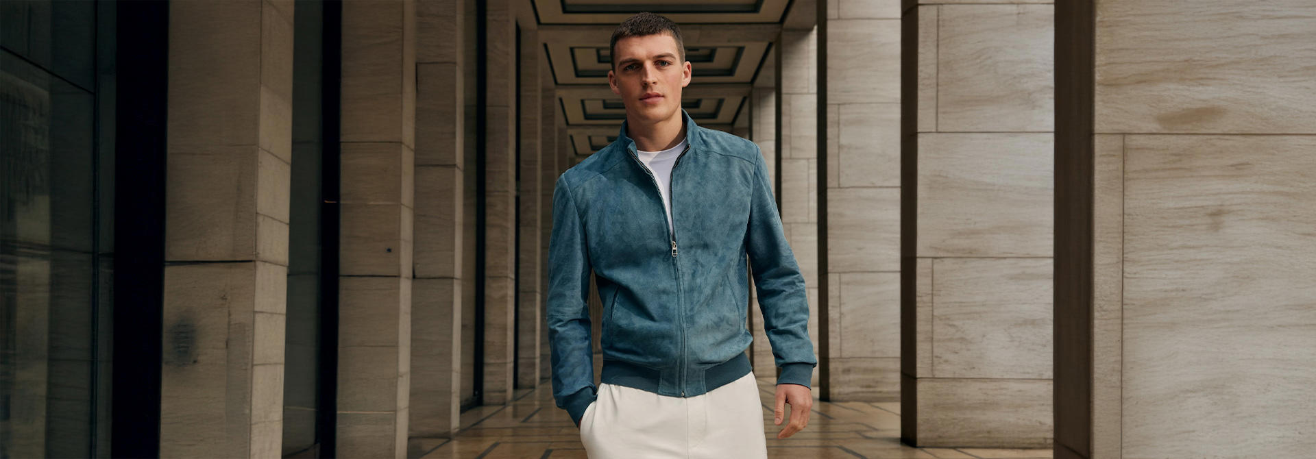 Ein junger Mann in einer blauen Velourslederjacke.