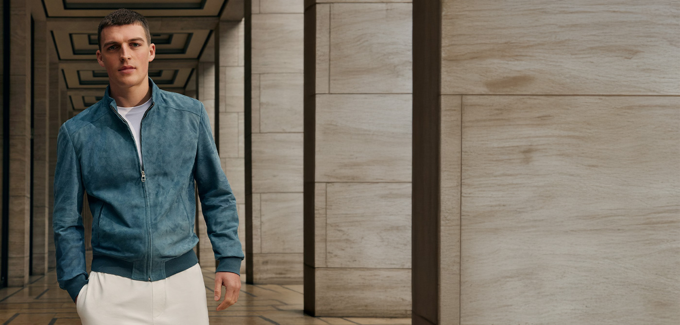 Ein junger Mann in einer blauen Velourslederjacke.