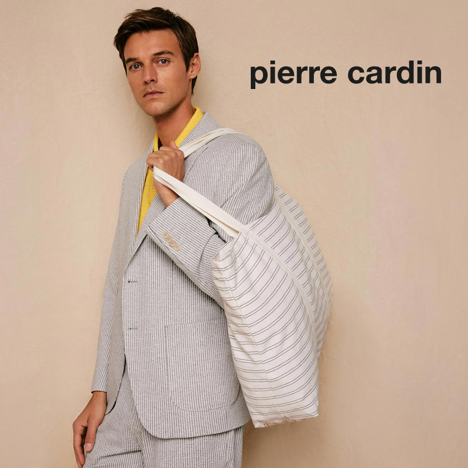 Stilvoller Mann mit gestreifter Jacke über der Schulter steht vor beigem Hintergrund – Mode von Pierre Cardin.
