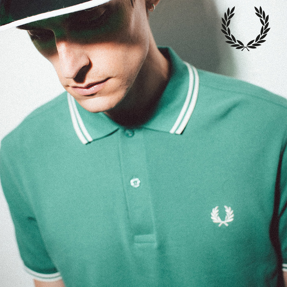 Nahaufnahme eines Mannes mit grünem Poloshirt von Fred Perry mit weißen Streifen am Kragen