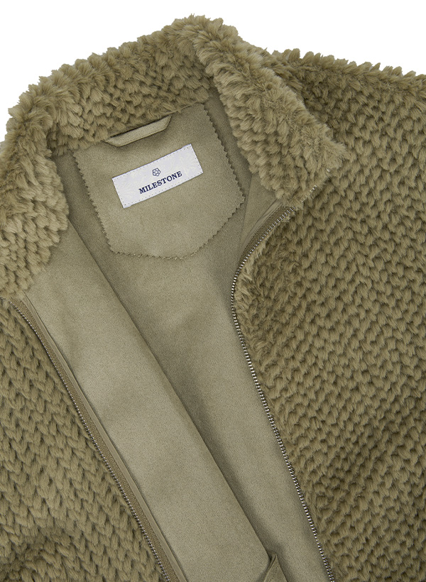 Eine Nahaufnahme einer Damenjacke aus olivgrünem Kunstfell mit Struktur