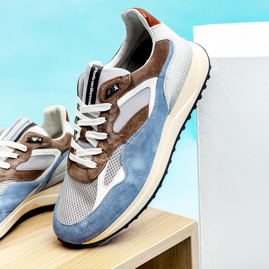 Moderne Sneaker in Blau und Braun mit weißer Sohle auf Holzwürfel.
