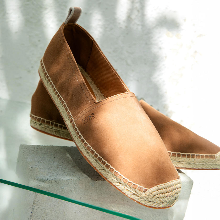 Hellbraune Espadrilles mit Bastsohle auf Glasplatte.