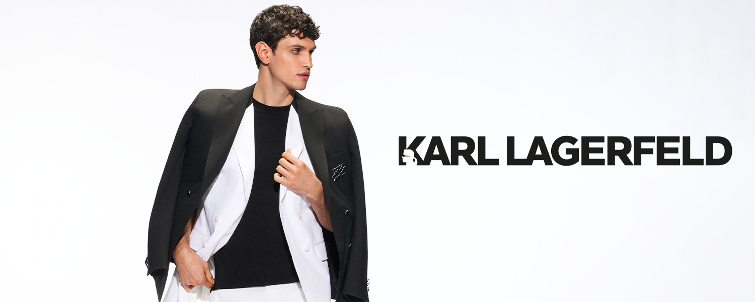 Ein junger Mann posiert in einem modernen schwarz-weißen Anzug-Look auf weißem Hintergrund mit dem Logo von Karl Lagerfeld.