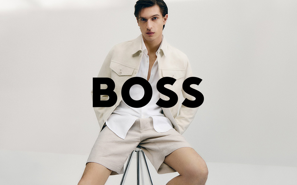 Ein junger Mann in BOSS gekleidet vor grauem Hintergrund, mittiges BOSS-Logo