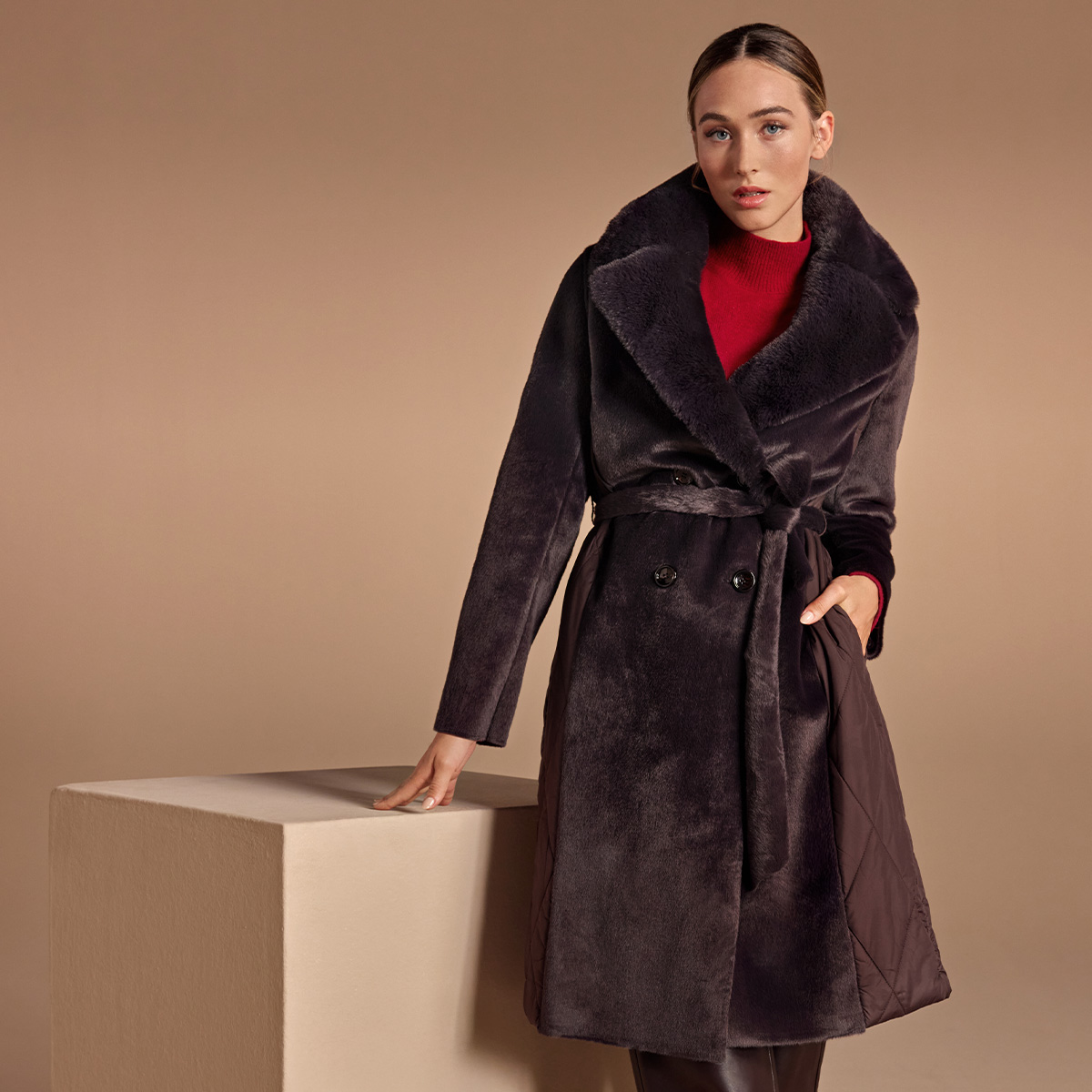 Eine Frau in Kunstpelzmantel vor neutralem Hintergrund