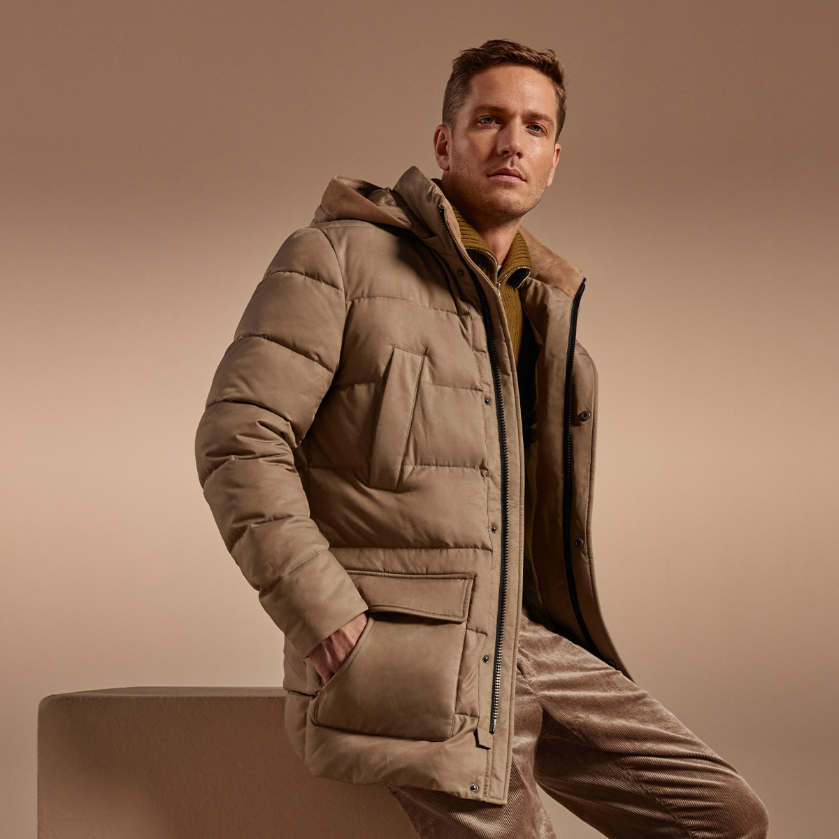 Ein Mann im Steppparka vor neutralem Hintergrund