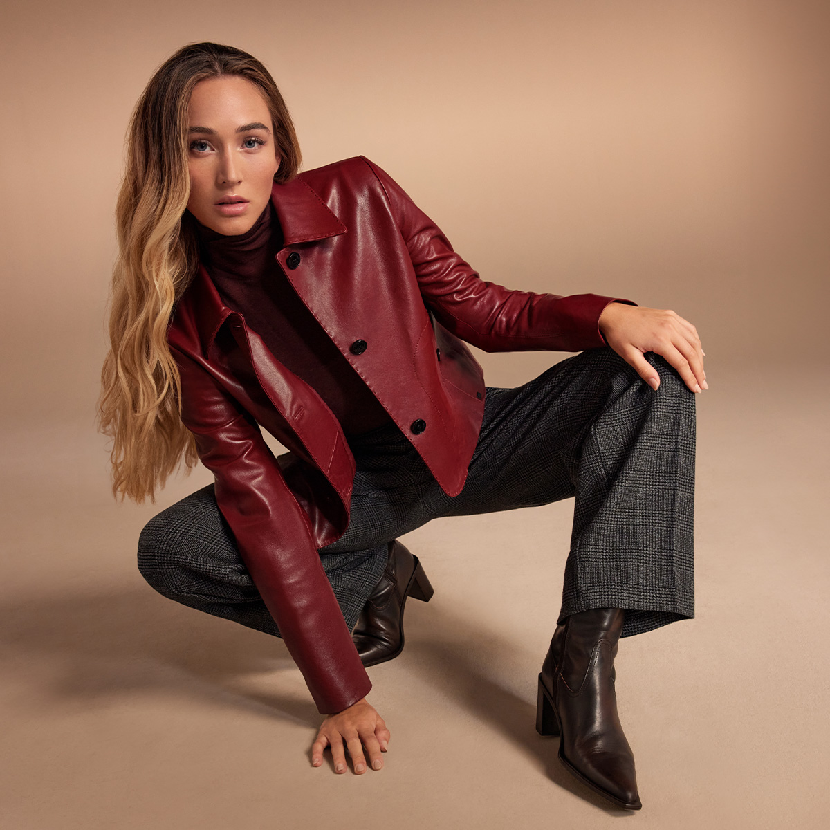 Eine Frau in dunkelroter Lederjacke vor neutralem Hintergrund