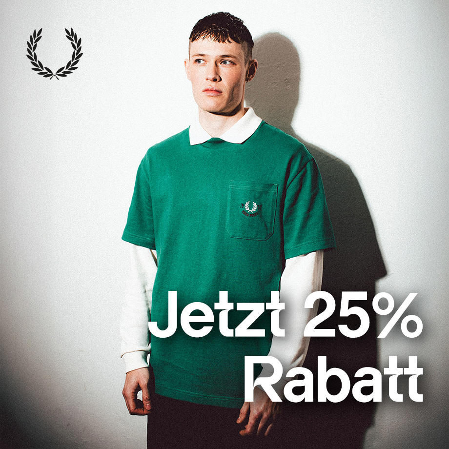 Junger Mann trägt ein grünes Fred Perry T-Shirt über einem weißen Langarmshirt und steht vor einer hellen Wand mit Schattenwurf; daneben steht der Schriftzug „Jetzt 25 % Rabatt“.