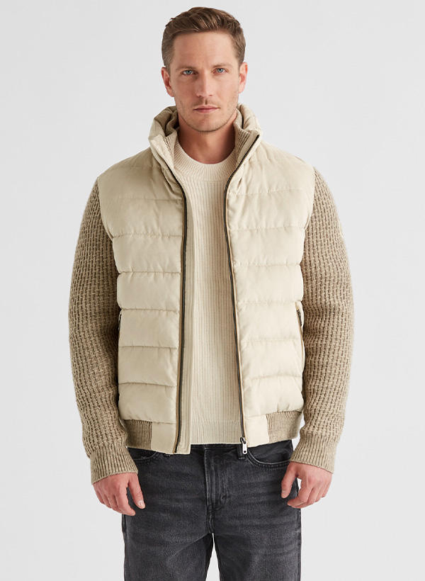 Ein Mann trägt eine beigefarbene Jacke mit Strickärmeln
