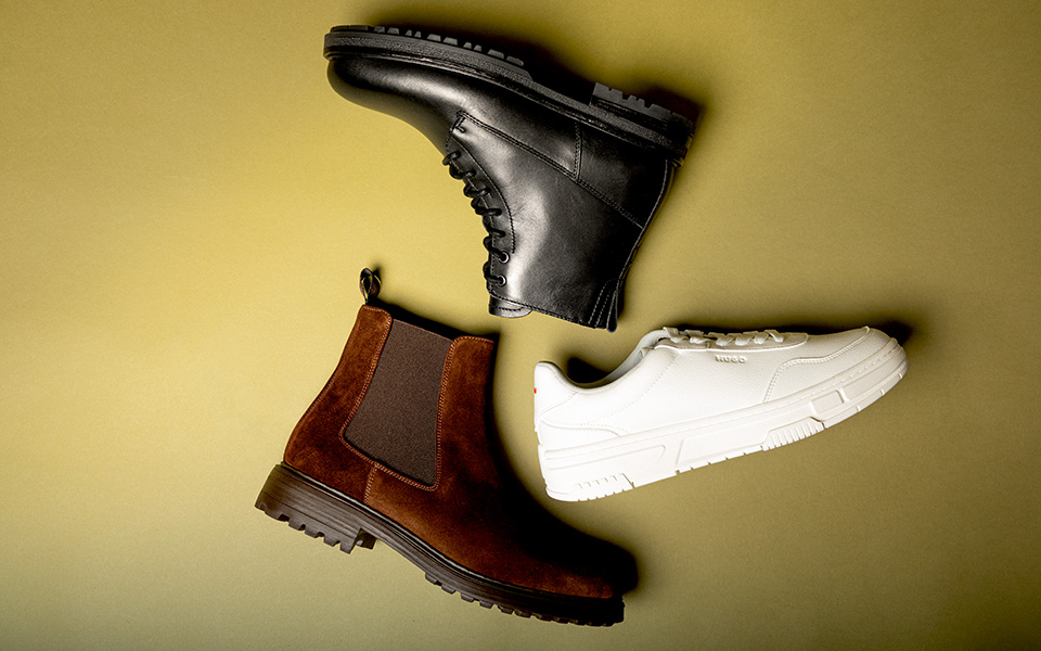 Ein Flatlay von 3 Schuhen auf grünem Untergrund.