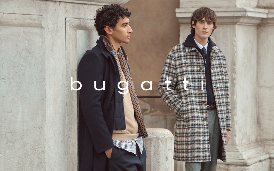 Zwei Männer in der Mode von bugatti stehen an einem historischen Gebäude. In der Mitte ist das Logo von bugatti.