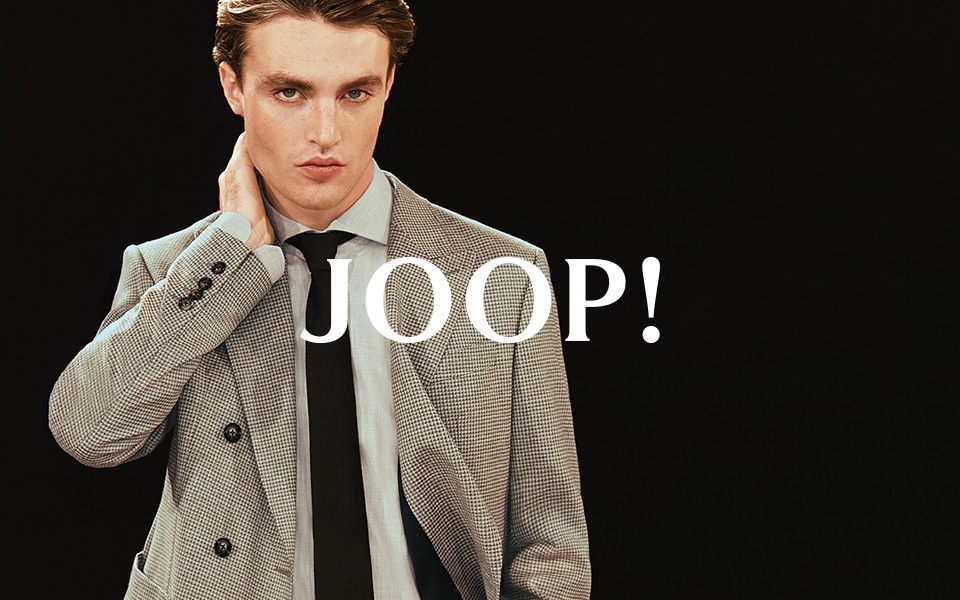 Ein Mann vor schwarzem Background in einem grauen JOOP-Anzug. In der Mitte ist das JOOP Logo