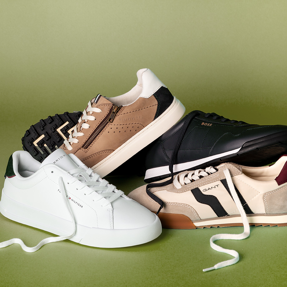 Einige Sneaker liegen auf einem grünen Hintergrund.