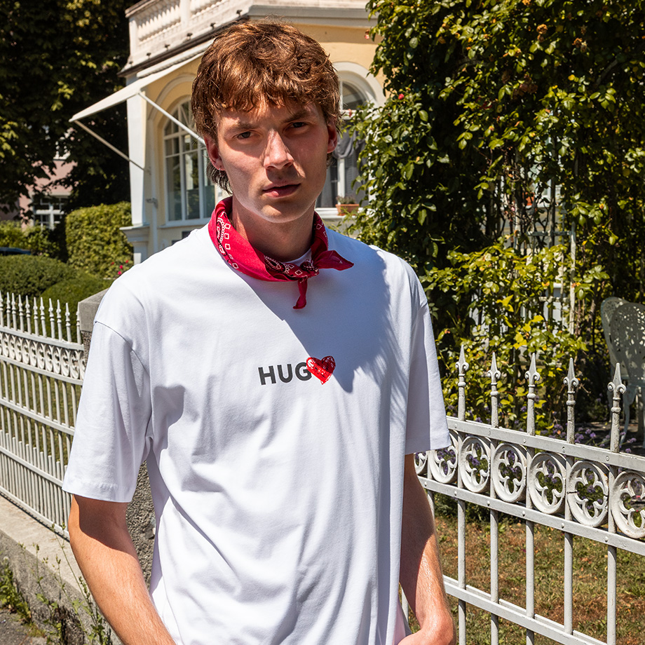 Ein junger Mann in einem weißen T-Shirt mit Herz-Print von HUGO