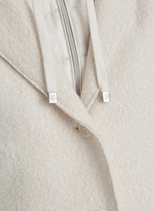 Nahaufnahme des Kragens eines Damenmantels mit Teddyfell und Materialmix