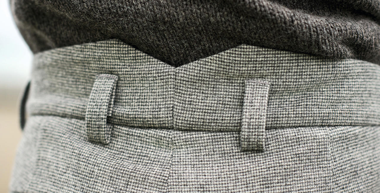 Detailaufnahme einer grauen Herrenhose mit feinem Karomuster und Bund.