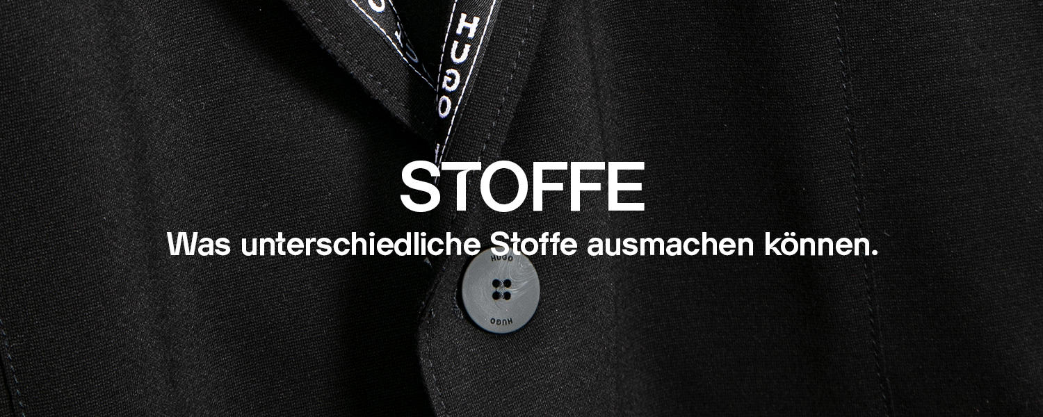 Nahaufnahme eines schwarzen Sakkos von Hugo Boss, das den feinen Stoff und die Struktur des Materials zeigt. Darüber steht die Überschrift „Stoffe – Was unterschiedliche Stoffe ausmachen können.“