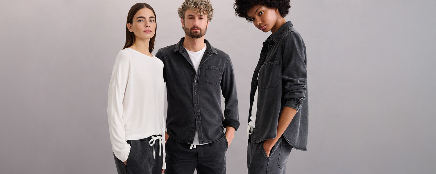 Drei Models tragen gemütliche Loungewear von Juvia – weißer Pullover und dunkle Relaxhosen kombiniert mit schwarzem Hemd und Shirt im modernen Casual-Look.