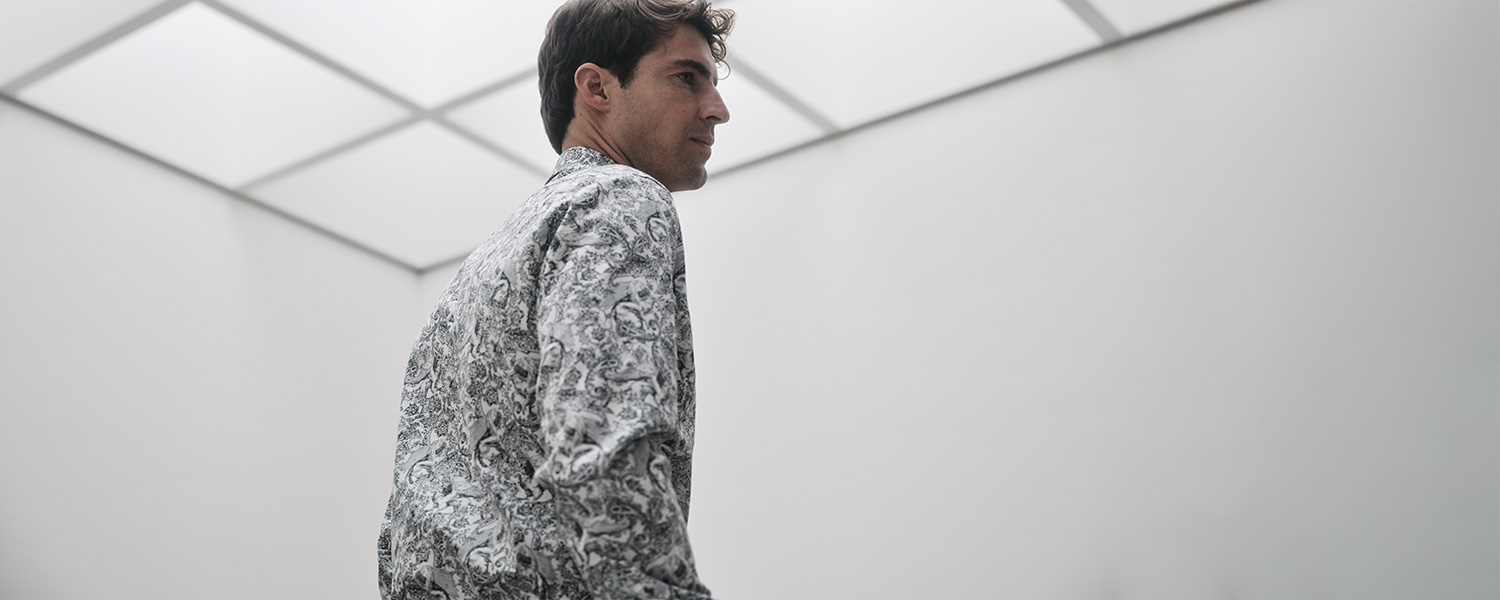 Mann trägt ein elegantes Eterna Hemd mit schwarz-weißem Muster, modern inszeniert in minimalistischer Architektur.