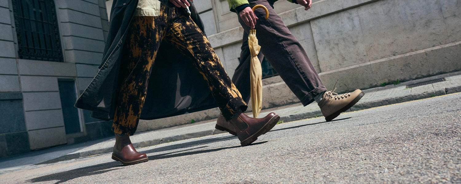 Zwei Personen laufen durch die Stadt, beide tragen trendige Birkenstock Boots in Braun und Beige – moderne Streetstyle-Schuhe für Herbst und Winter.