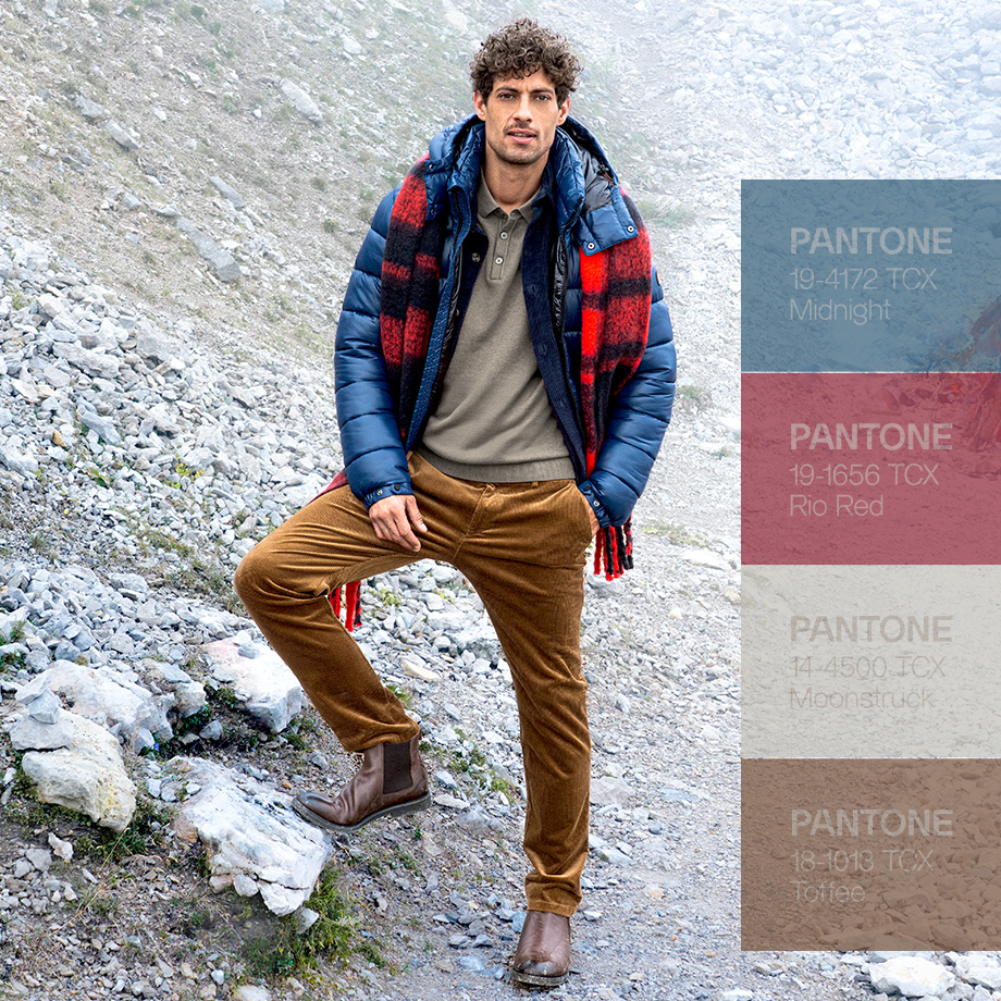 Mann in Outdoor-Outfit mit Daunenjacke, Cordhose und kariertem Schal in Pantone-Farben Midnight, Rio Red, Moonstruck und Toffee – herbstliche Herrenmode inspiriert von Naturtönen.