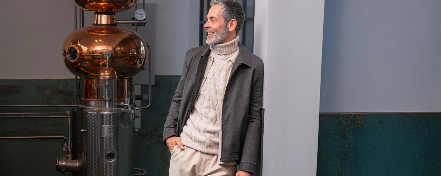 Eleganter Blouson in Grau, kombiniert mit einem beigen Zopfmuster-Rollkragenpullover – stilvoller Look für die kalte Jahreszeit.