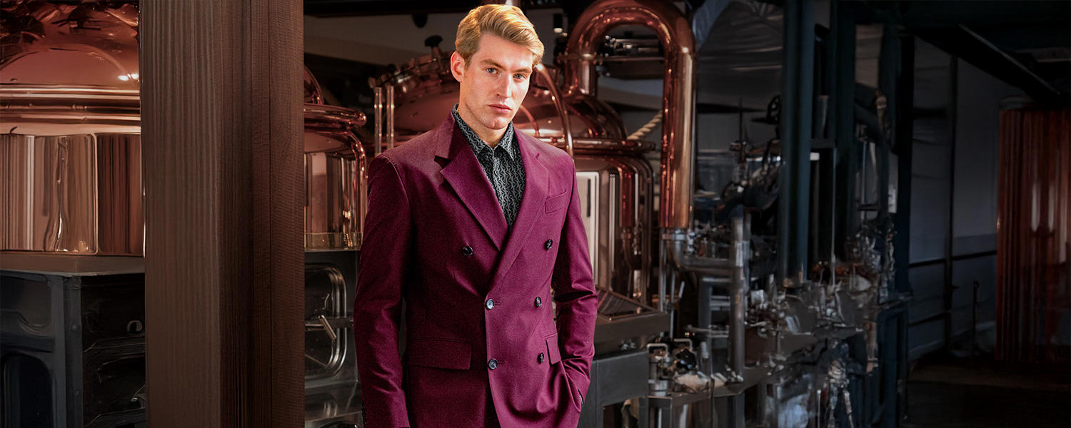 Auf dem Bild trägt ein Mann ein elegantes, weinrotes Sakko mit doppelter Knopfreihe – stilvoll kombiniert für formelle Anlässe.