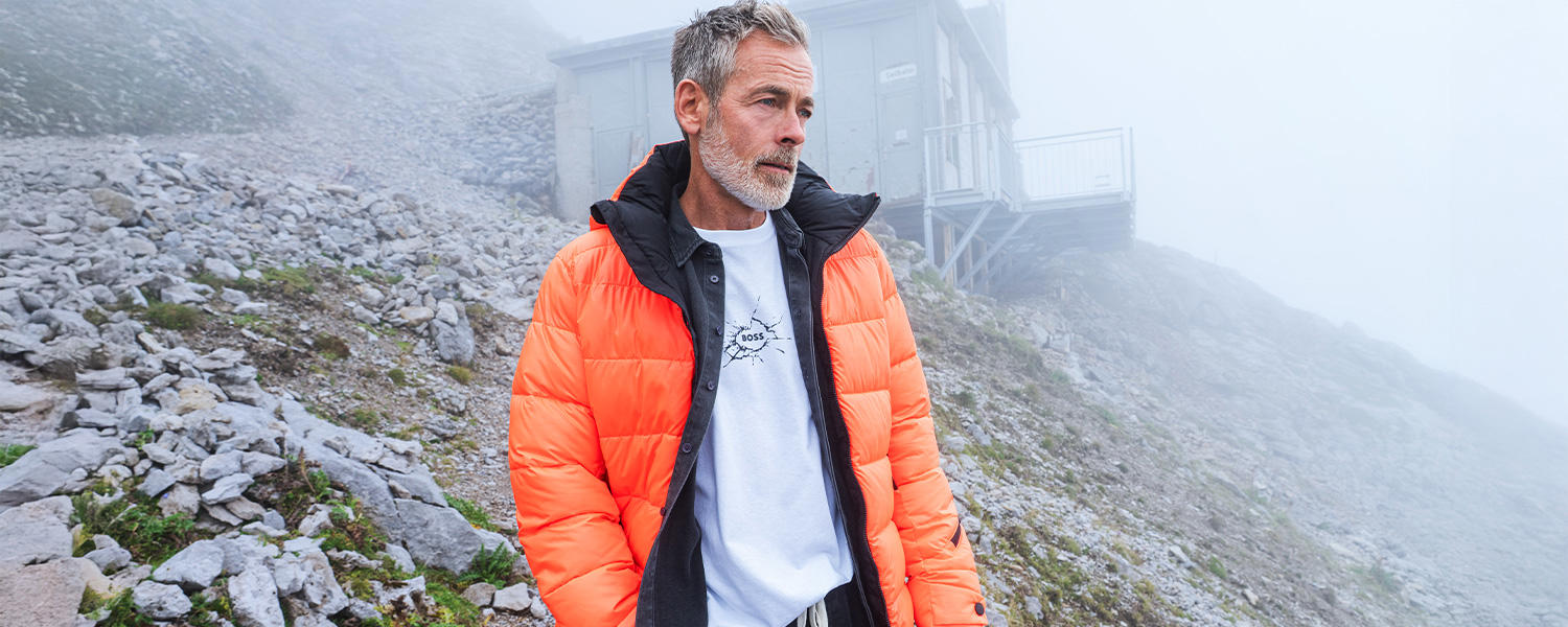 Leuchtend orangefarbene Herren-Steppjacke mit sportivem Charakter – ideal für kalte Tage und lässige Outdoor-Looks.