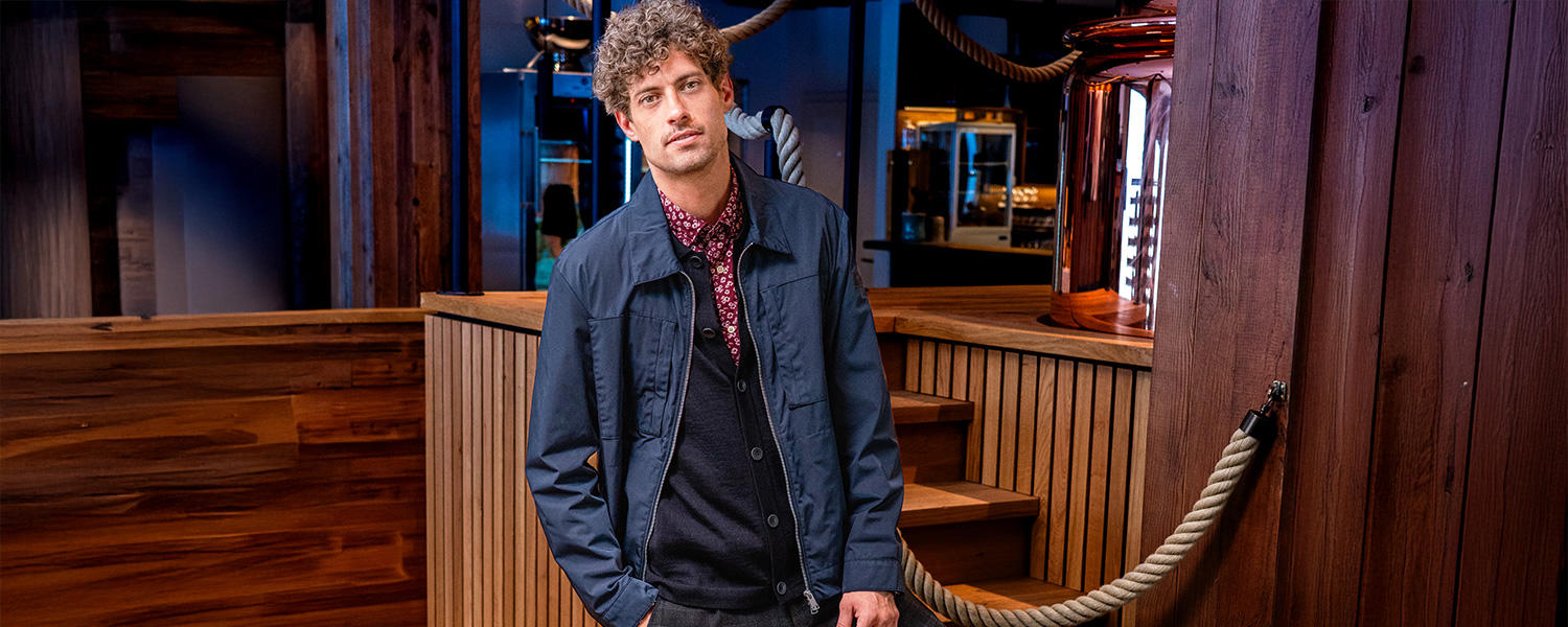 Klassisches Fieldjacket in Dunkelblau, kombiniert mit gemustertem Hemd und Strickjacke – ein vielseitiger Look für Alltag und Freizeit.