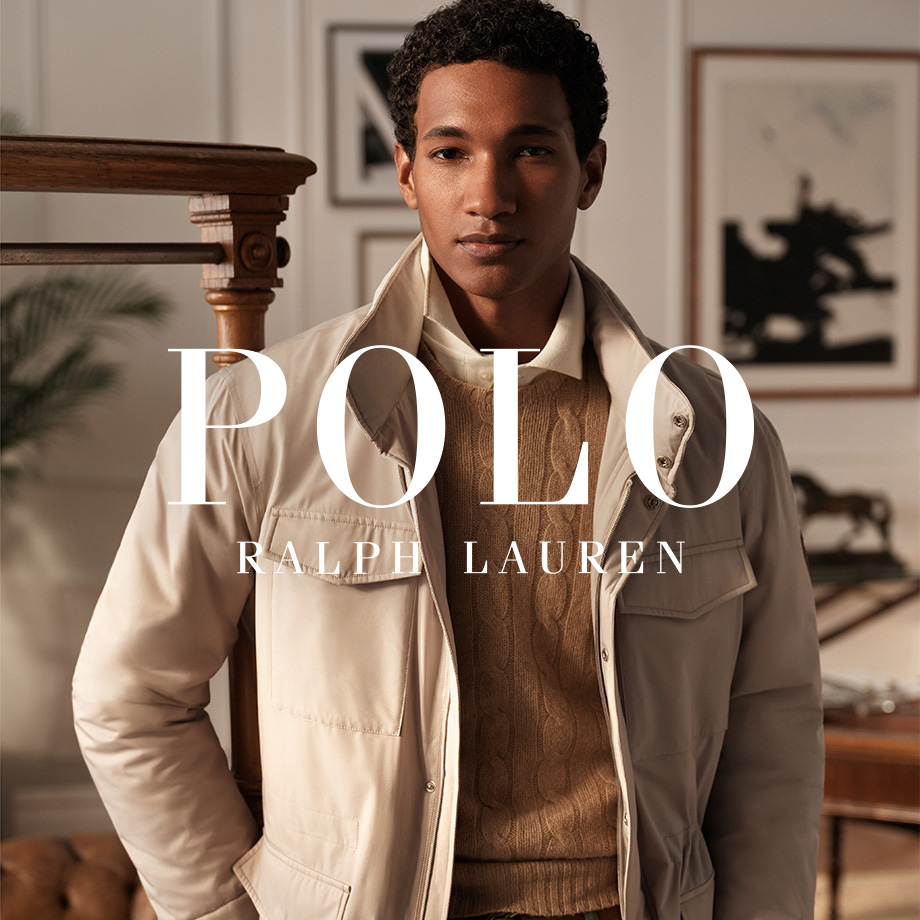 Mann in heller Jacke mit beigem Strickpullover und Hemd von Polo Ralph Lauren, stehend im Arbeitszimmer.