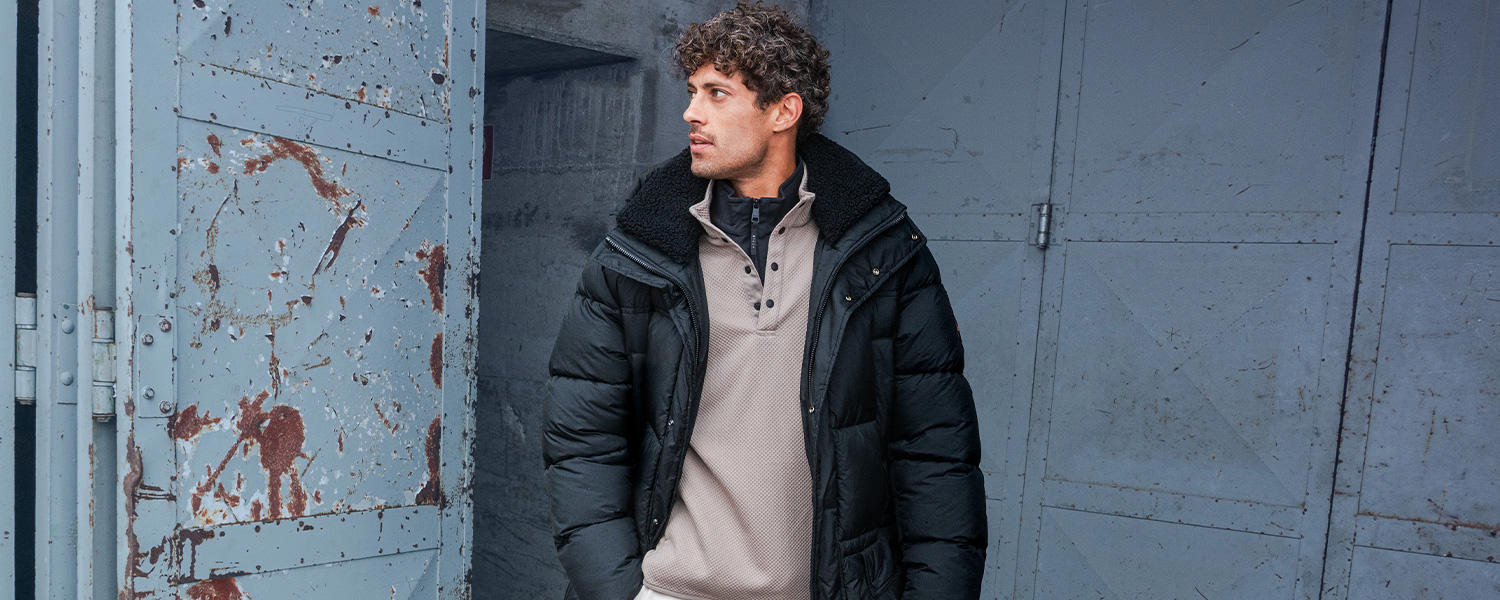 Auf dem Bild trägt ein Mann ein graues Sweatshirt unter einer schwarzen Steppjacke.