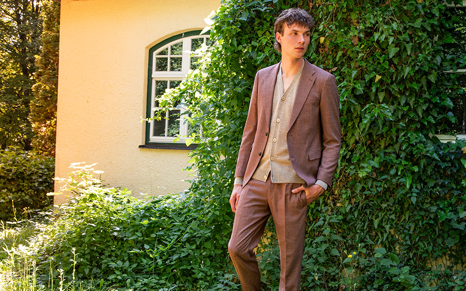 Ein junger Mann trägt einen rotbraunen Herbstanzug, lässig-elegant gestylt.