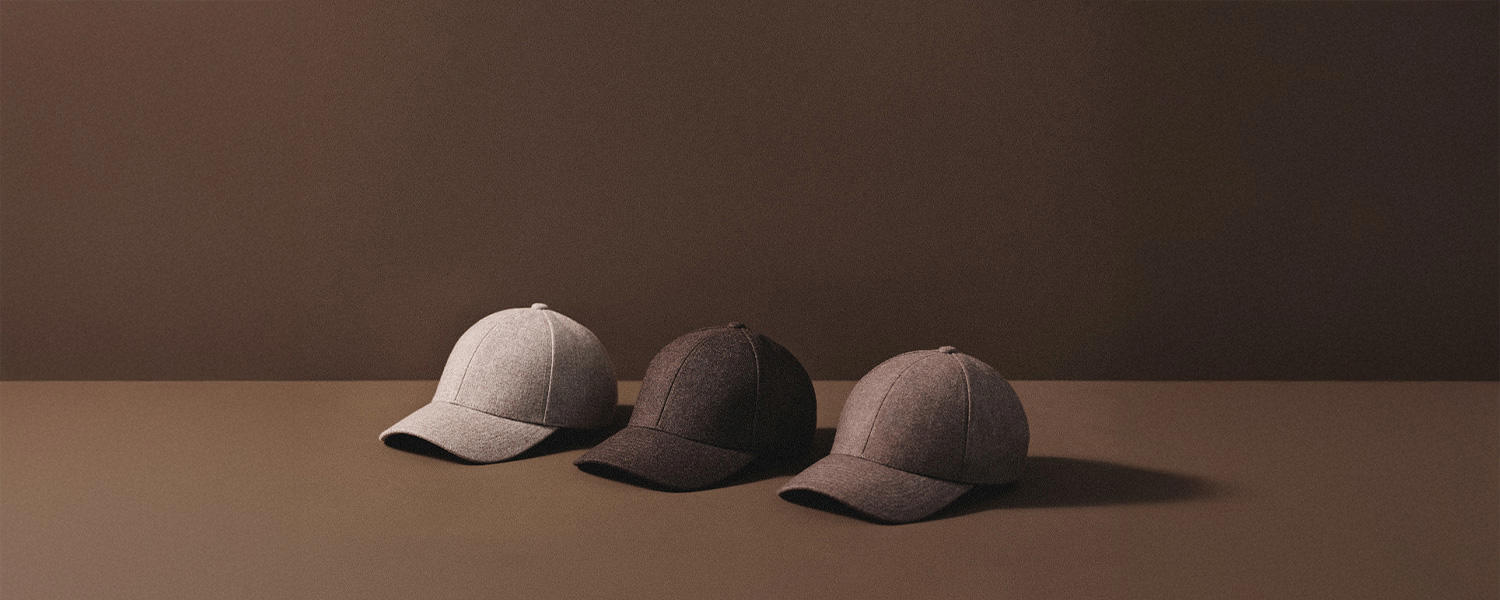 Ein minimalistisches Markenmotiv von Varsity: Drei schlichte, hochwertige Caps in Grau- und Brauntönen sind vor neutralem Hintergrund arrangiert – Symbol für skandinavisches Design, Understatement und Premium-Accessoires.