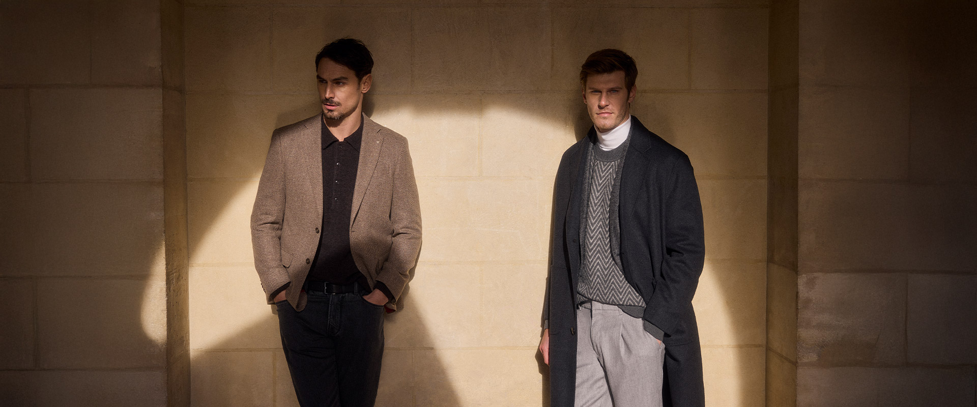 Zwei Männer in eleganten Outfits: braunes Sakko mit Poloshirt und dunklem Look, daneben grauer Mantel über Strick, stilvoller Business-Casual.