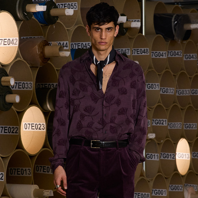 Dunkelviolettes Hemd mit Muster, kombiniert mit Cordhose und lockerem Schal, modischer Retro-Look.
