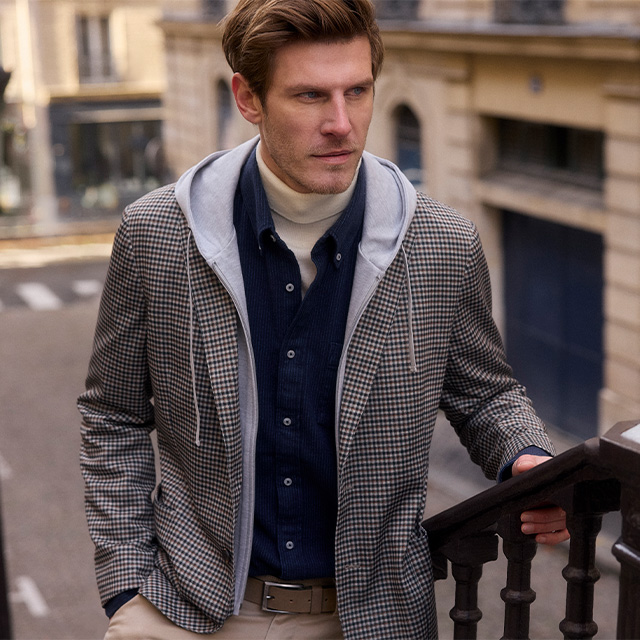 Gemustertes Sakko mit grauem Hoodie, kombiniert mit Rollkragen und Hemd, smarter Streetstyle-Mix.