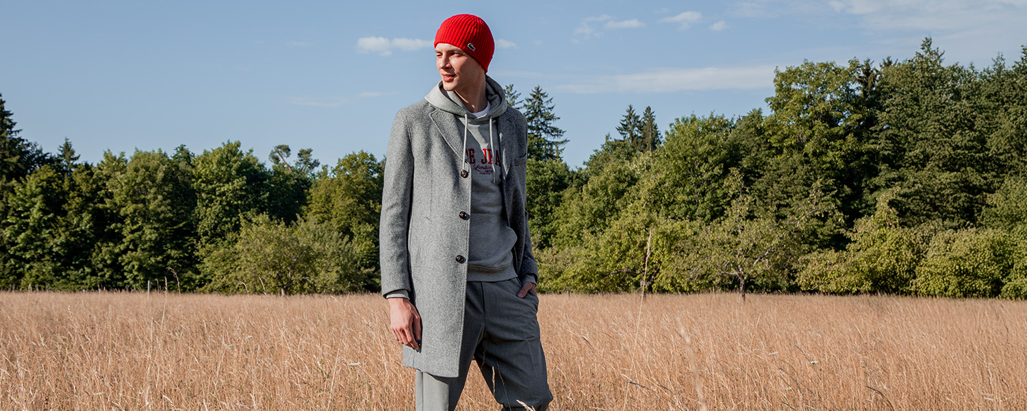 Grauer Wollmantel mit roter Mütze – lässig-eleganter Herbst-Look mit Hoodie und Anzughose.